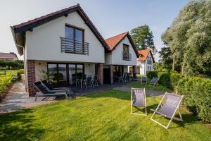 a house with two lawn chairs in the yard at Trzy Wyspy Barlinek in Barlinek