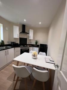a white kitchen with a table and chairs in it at Pinfold Court Apartments in Knowsley