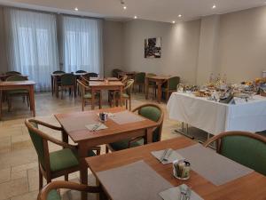un comedor con mesas y sillas de madera y una mesa. en Hotel Lux, en Alessandria