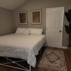 a bedroom with a bed with white sheets and a rug at Stylish Cottage Near Airport in Atlanta