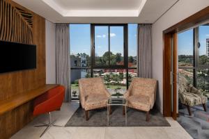 a living room with two chairs and a flat screen tv at Holiday Inn - Nairobi Two Rivers Mall, an IHG Hotel in Nairobi