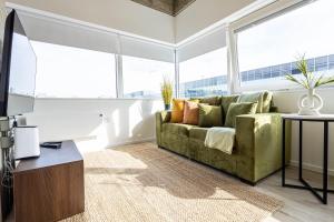a living room with a green couch and large windows at Stunning City View Apartments in Milton Keynes Central Location Free Parking in Milton Keynes