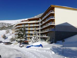 un hotel nella neve con le auto parcheggiate di fronte di Appartement Huez, 1 pièce, 2 personnes - FR-1-405-139 a LʼAlpe-dʼHuez