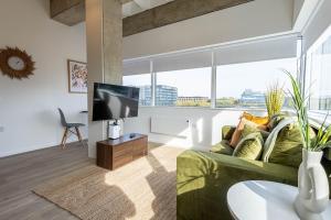 a living room with a green couch and a tv at Stunning City View Apartments in Milton Keynes Central Location Free Parking in Milton Keynes