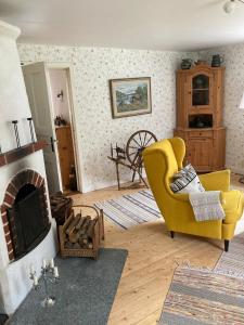 a living room with a yellow chair and a fireplace at Furulund in Linneryd