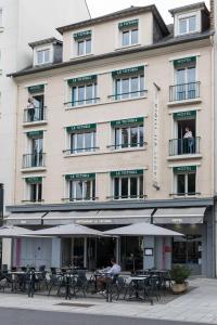 un edificio con tavoli e ombrelloni di fronte ad esso di Hotel-Restaurant Le Victoria a Rennes