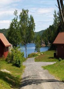 a gravel road next to a river with two buildings at Risør Gjestehus in Risør