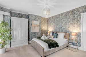 a bedroom with a large bed with floral wallpaper at Guest Homes - Gorleston Sands Retreat in Gorleston-on-Sea