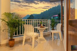 een balkon met een tafel en stoelen bij The Hillside inn by Exotic Stays in Kasauli