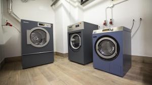 3 lavatrici e asciugatrice in lavanderia di Hotel Nevada a Tarvisio