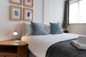 een slaapkamer met een groot wit bed met blauwe kussens bij Milton Mews - Spacious and modern 3 bedroom apartment in Portsmouth in Portsmouth