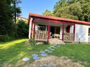 ein kleines Cottage mit einer Veranda und einem Tisch auf dem Rasen in der Unterkunft Chalet de 3 chambres avec piscine partagee jacuzzi et jardin amenage a Hasparren in Hasparren