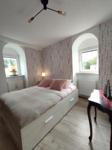 a bedroom with a large white bed and two windows at Apartament 44 in Lądek-Zdrój