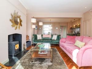 a living room with a pink couch and a fireplace at Astondene in Southwold