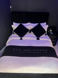 Cama con manta y almohadas blancas y negras en The Arc Suites en Bradford