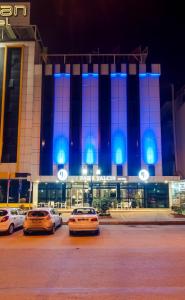 drie auto's geparkeerd voor een gebouw 's nachts bij PARK YALÇIN HOTEL in Mersin