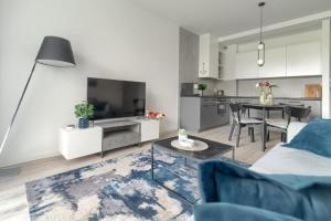 a living room with a blue couch and a kitchen at Ground floor apartment with a garden in Niechorze in Niechorze +15 photos
