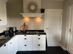 a kitchen with white cabinets and a black counter top at Vakantiehuisje de Wender in Ambt Delden