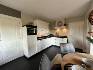a kitchen with white cabinets and a table and chairs at Vakantiehuisje de Wender in Ambt Delden