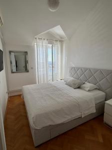 a white bedroom with a large bed and a mirror at Villa Iva in Dubrovnik