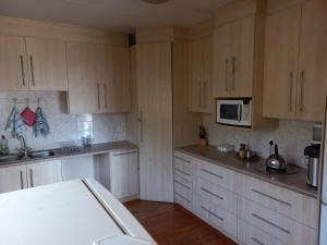 a kitchen with white cabinets and a white microwave at Twogether House in Clarens