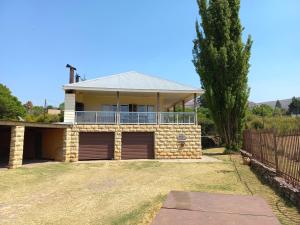 a house with a balcony and a yard at Twogether House in Clarens