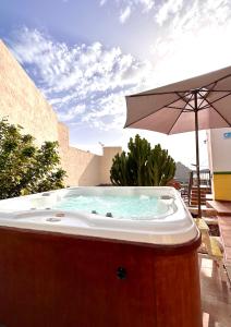 a hot tub with an umbrella on a patio at Casa Regina Tenerife in Tamaimo