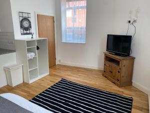 a living room with a television on a wooden table at Midland apartments- Open plan in Leicester