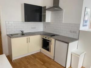 una cocina con armarios blancos y fregadero en Midland apartments- Open plan, en Leicester