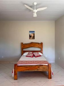 Schlafzimmer mit einem Holzbett und einem Deckenventilator in der Unterkunft Casa de Praia Recanto do Atlântico in Nova Viçosa
