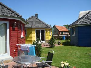 une maison jaune avec une table et des chaises dans une cour dans l'établissement Gelb-Peters, à Börgerende-Rethwisch
