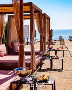 Grand Sapphire Resort Residence -Mansion de la Mer في Saint Yeorgios: شاطئ به عدة أسرة وطاولات على الشاطئ