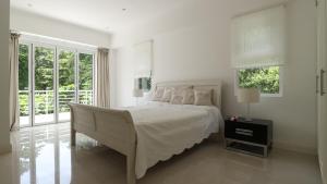 a white bedroom with a large bed and windows at Las Brisas Villa - Chateau Elysium in Beau Vallon +28 photos