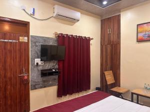 ein Schlafzimmer mit einem roten Vorhang und einem TV in der Unterkunft The Peninsulla in Rishikesh
