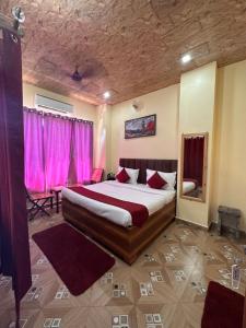 a bedroom with a large bed and pink curtains at The Peninsulla in Rishīkesh