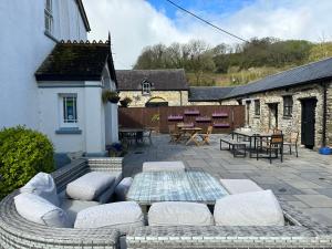 a patio with a couch and a table and chairs at Coach House at Picton - Restaurant and bar on site in St Clears