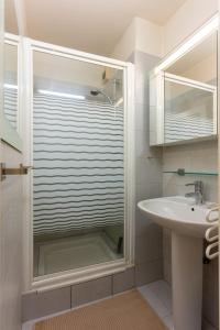 ein Badezimmer mit einer Glastür neben einem Waschbecken in der Unterkunft L'Échappée Courbevoie - 2 Chambres in La Défense