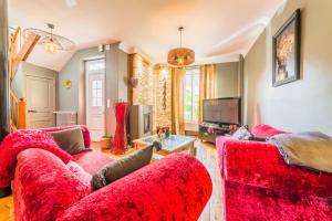 ein Wohnzimmer mit zwei roten Sofas und einem TV in der Unterkunft SELVES 8 - Maison Jacuzzi in Brive-la-Gaillarde