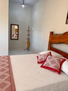 Schlafzimmer mit einem Bett mit roten Kissen und einem Spiegel in der Unterkunft Casa de Praia Recanto do Atlântico in Nova Viçosa