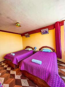 two beds in a room with purple sheets at Hostal Sol y Lago in Copacabana