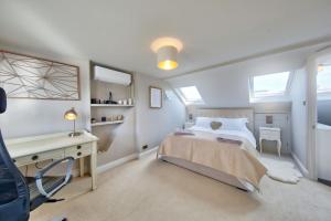 Schlafzimmer mit einem Bett, einem Schreibtisch und Fenstern in der Unterkunft Family 4-Bed House & Secluded Garden - Wimbledon in London