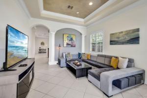 a living room with a couch and a flat screen tv at CocoBreeze - Poolside Paradise Mins to Beach! in Naples