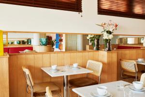 a restaurant with two tables and chairs and flowers at Hôtel California in Le Lavandou