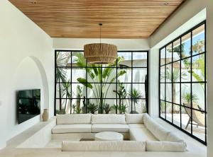 a living room with a white couch and large windows at Melrose x The Young Villas in Uluwatu