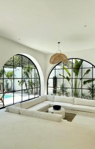 a living room with a white couch and large windows at Melrose x The Young Villas in Uluwatu