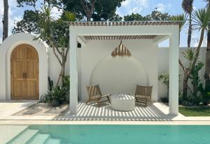 a patio with two chairs next to a swimming pool at Melrose x The Young Villas in Uluwatu