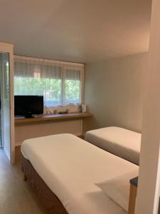 a hotel room with two beds and a television at Kyriad Direct Montpellier Saint Jean De Védas - La Peyrière in Saint-Jean-de-Védas