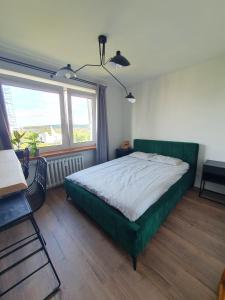 a bedroom with a green bed and a window at Apartamenty Cześć Kraków in Krakow