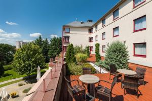 uma varanda com mesas e cadeiras e um edifício em Castrum Hotel Székesfehérvár em Székesfehérvár