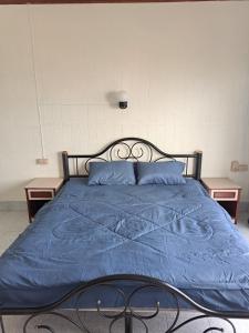 a bed with a blue comforter and two tables at Bo House in Patong Beach